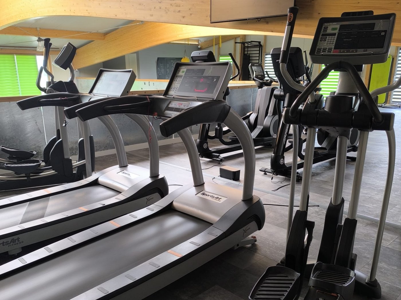Espace cardio aménagé avec tapis de course et vélos elliptiques dans une salle d’entraînement