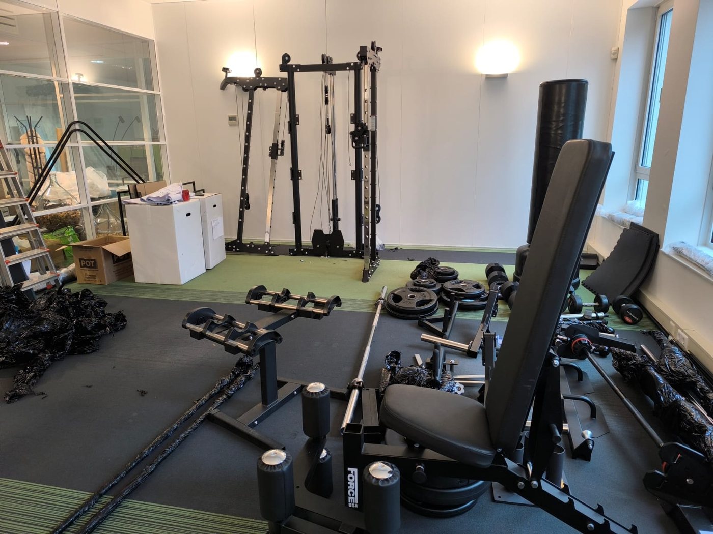 Unpacked components of a cable station in a training room, packaging film still on the floor