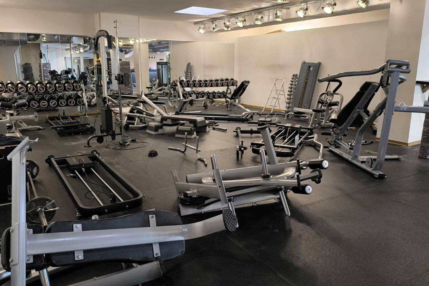 Strength machines and benches being assembled across a training room floor