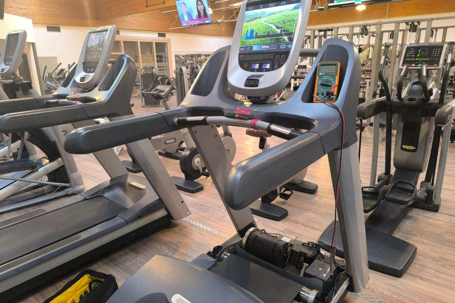 Multimètre fixé à la console d’un tapis de course de salle pendant une mesure électrique