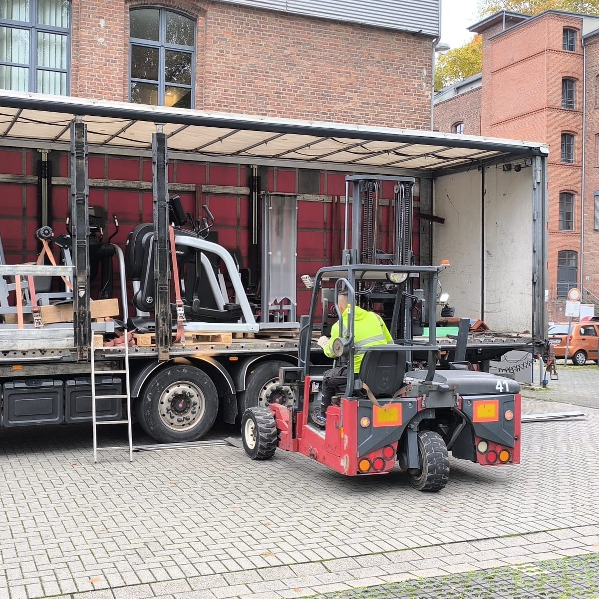 Appareils de fitness démontés sur le plateau d’un camion, chariot élévateur en cours de chargement