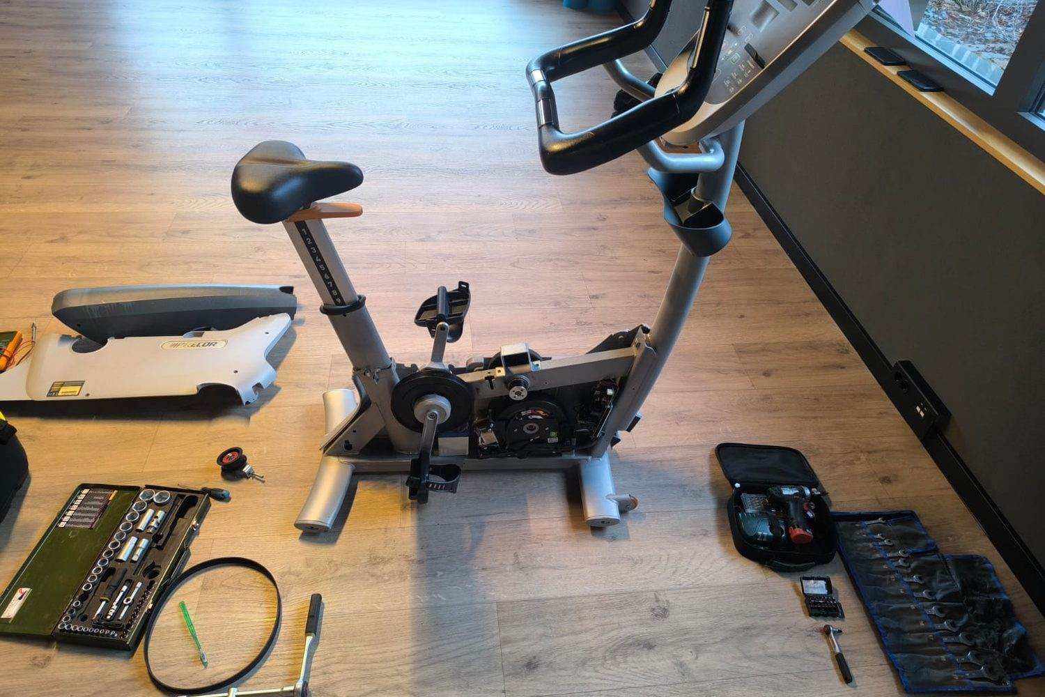 Vélo d’appartement démonté pour entretien, outils posés à côté