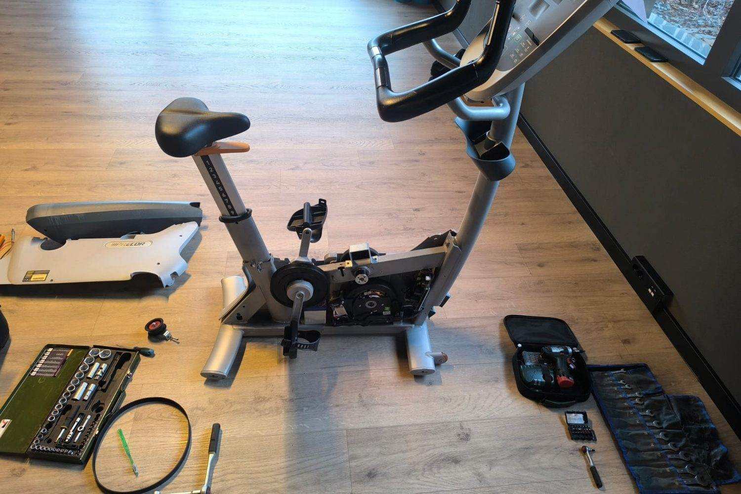 Exercise bike opened up for servicing with tools laid out beside it