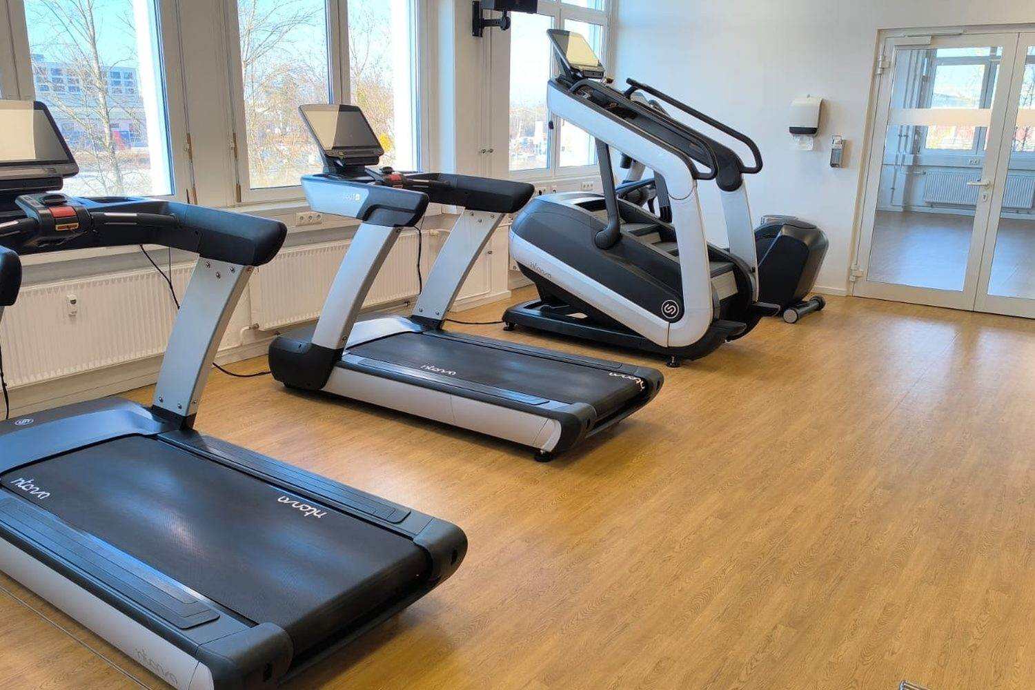 Fitness room in Luxembourg with a row of treadmills and a stair climber