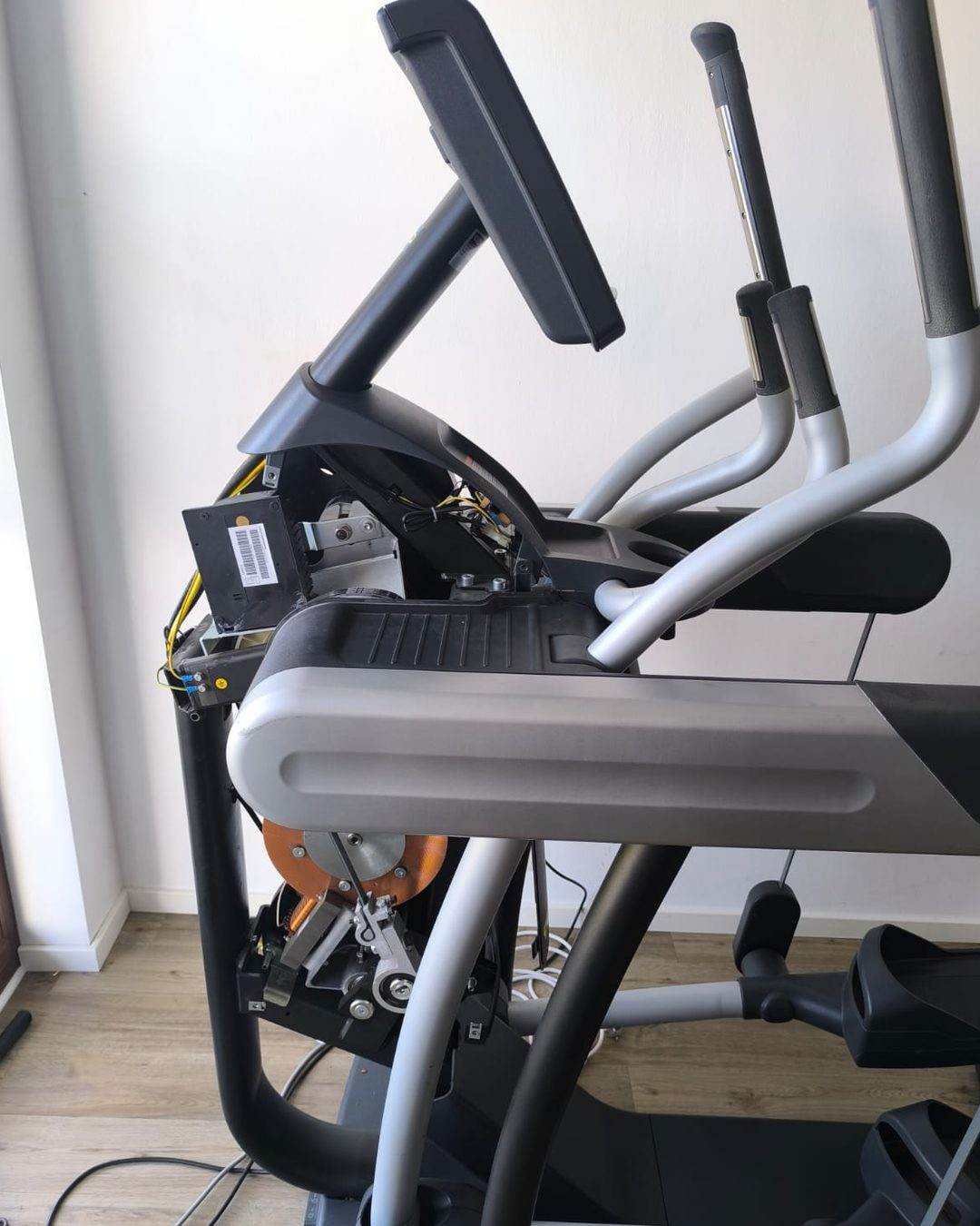 Geöffneter Crosstrainer bei der Reparatur: demontierte Konsole, sichtbare Elektronik und Antriebseinheit