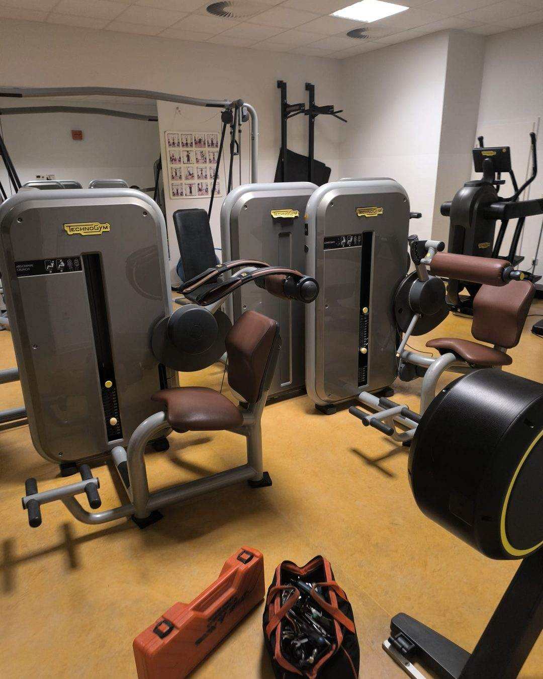 Training room with selectorized strength machines, the technician tool case and bag set down on the floor