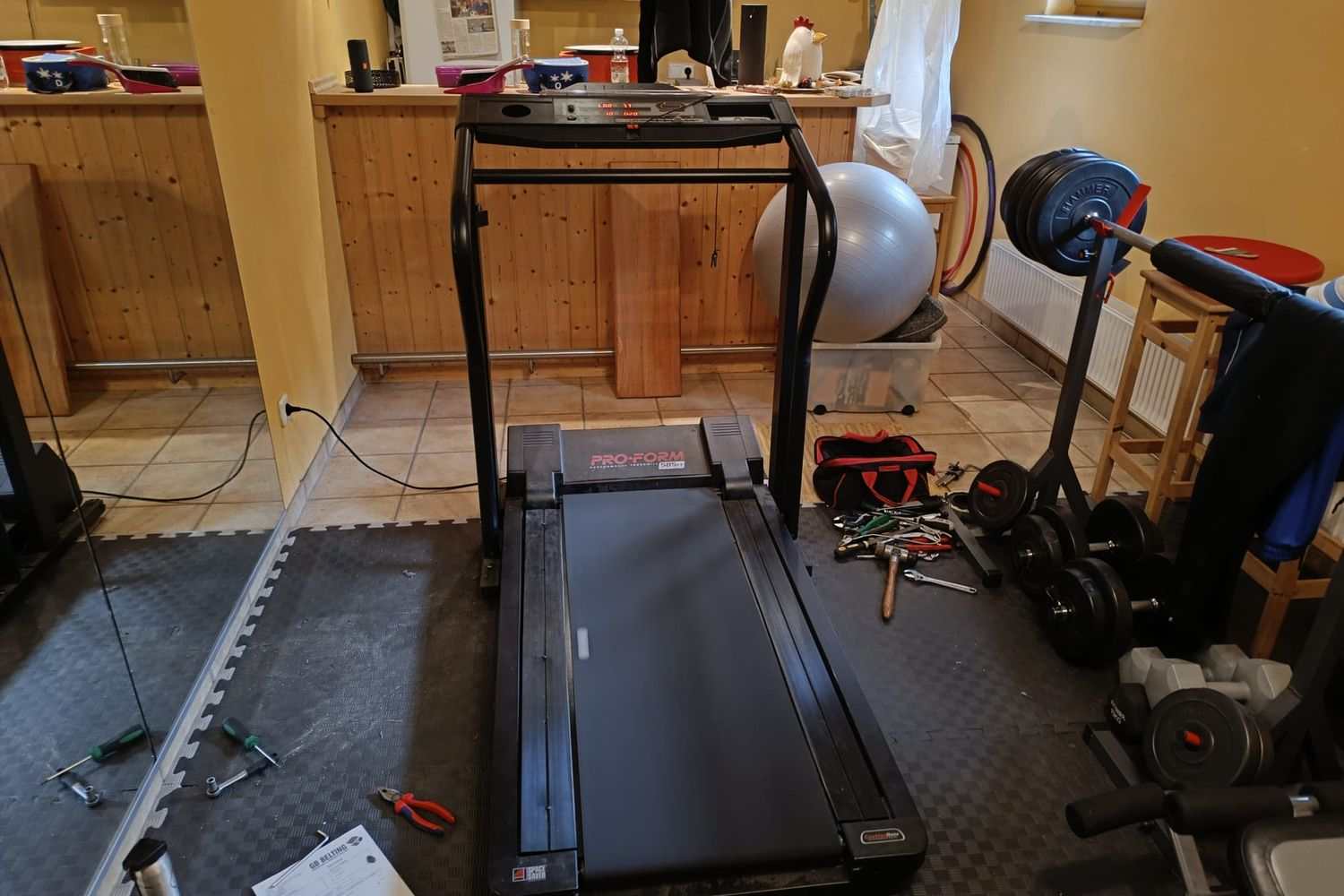 Treadmill repair in a private household, tools spread out on the basement floor