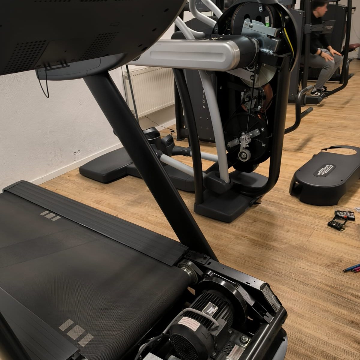 Tapis de course et vélo elliptique ouverts sur le plateau cardio d’une salle de sport