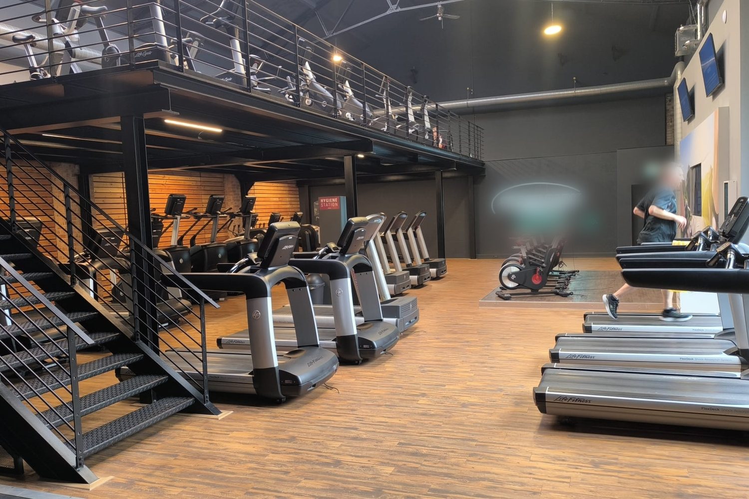 Plateau cardio entièrement aménagé d’un club avec tapis de course, elliptiques et mezzanine