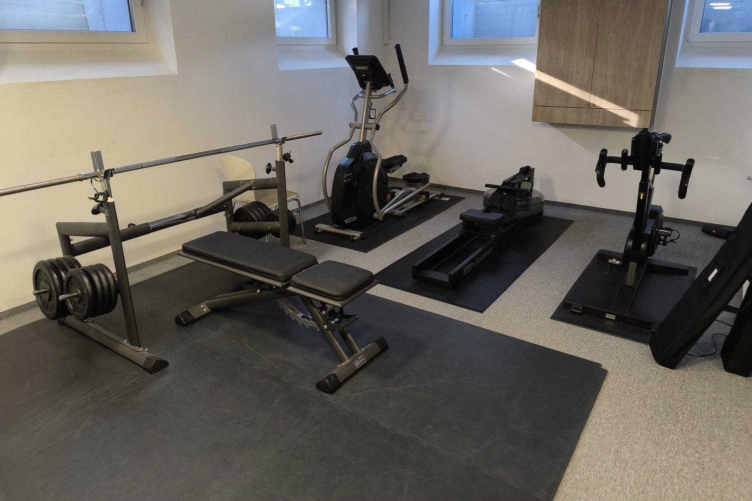 Petite salle de sport avec banc, vélo elliptique, rameur et vélo indoor