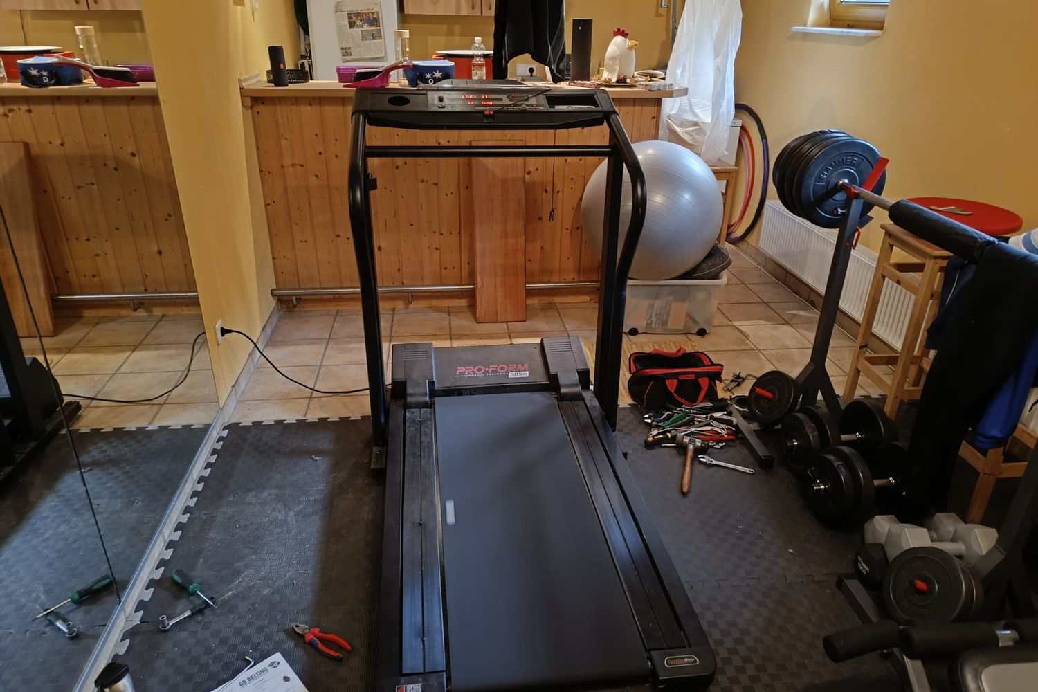 Réparation d’un tapis de course chez un particulier, outillage étalé sur le sol du sous-sol