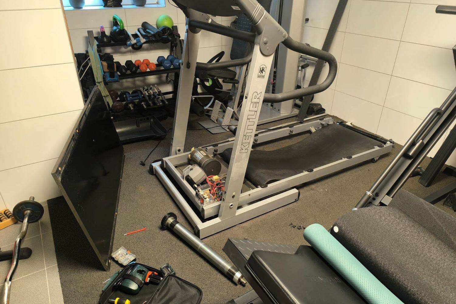 Tapis de course ouvert pour réparation, moteur d’entraînement et rouleau déposé visibles