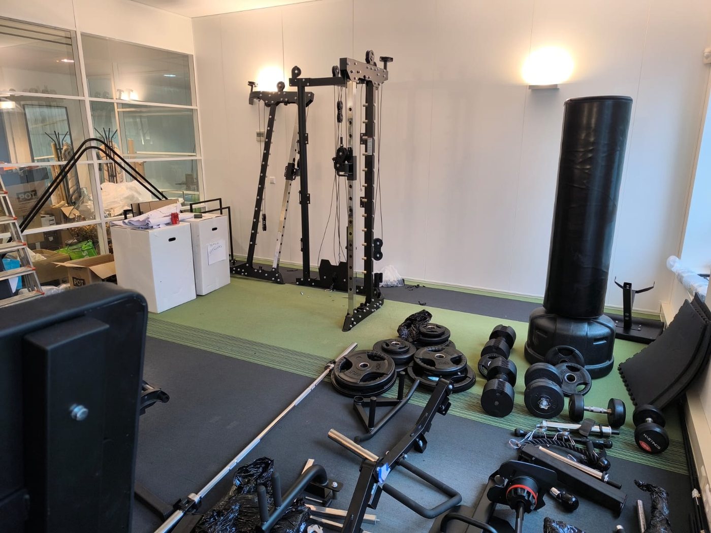 Cadre de la station de musculation dressé, disques et petites pièces triés au sol
