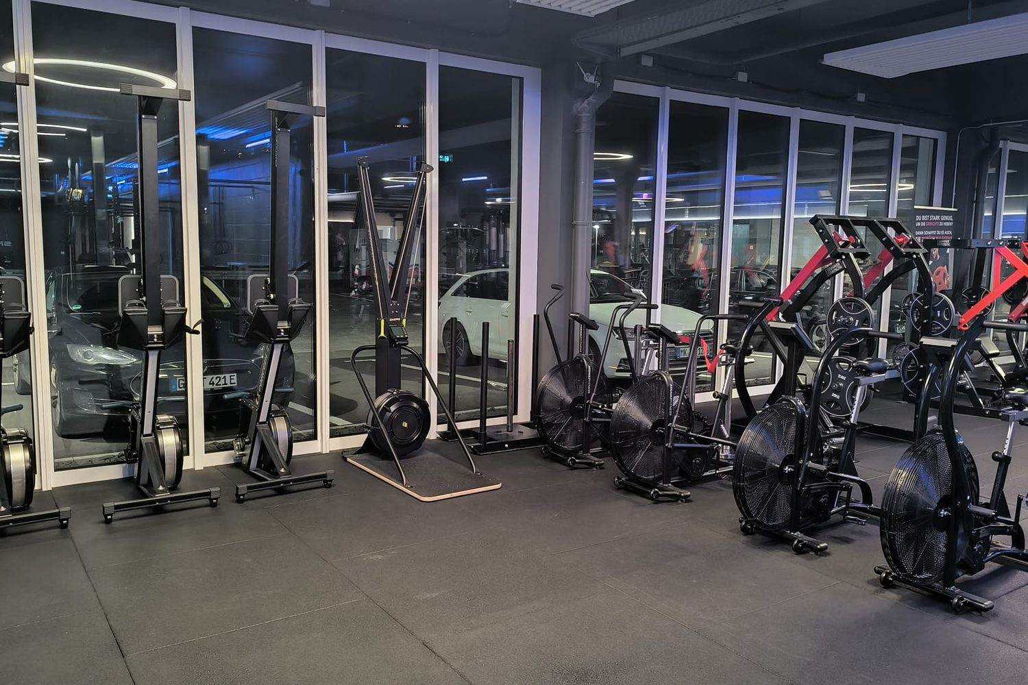 Espace cardio d’une salle moderne avec rameurs, ski ergomètre et vélos à air