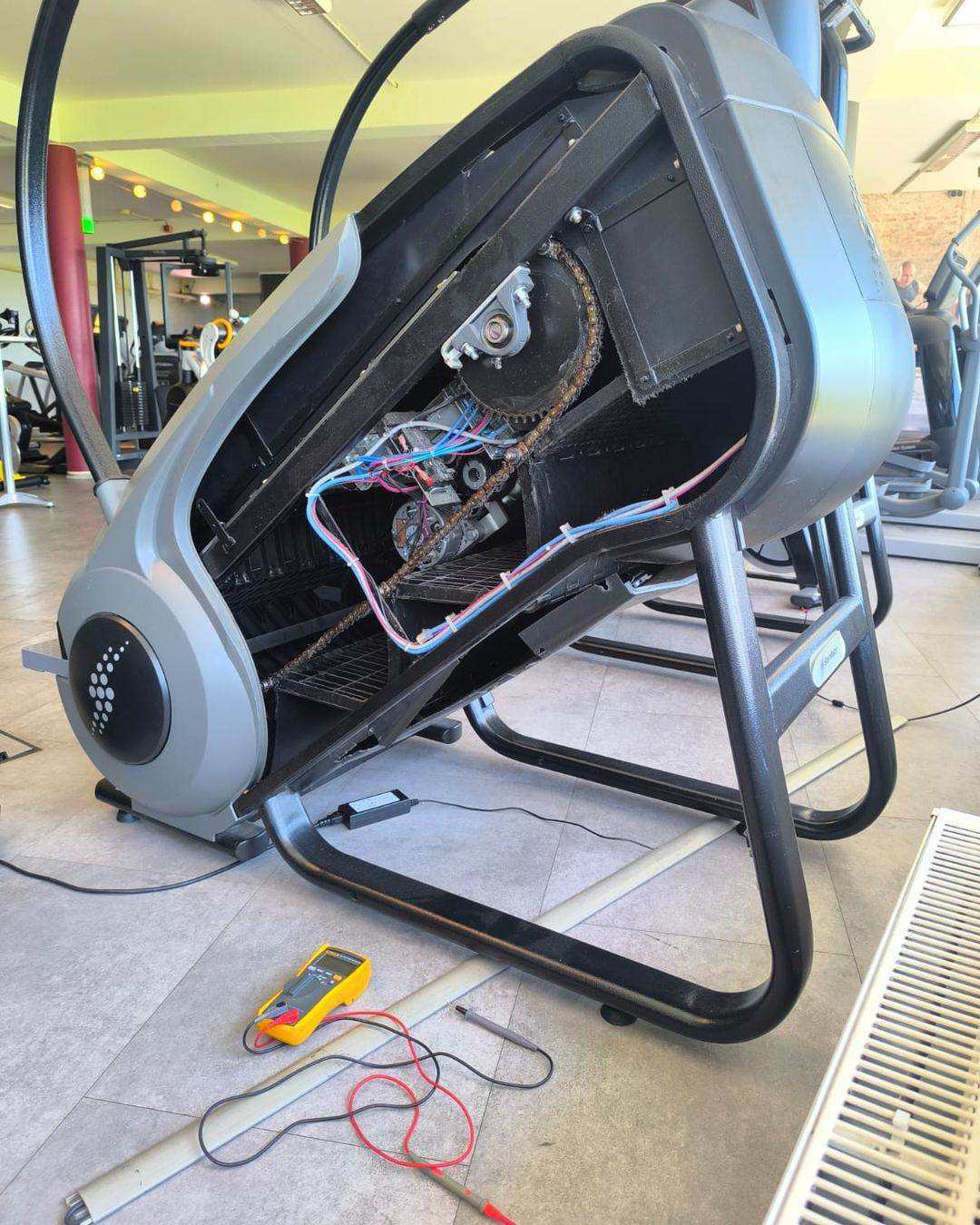 Stair climber opened for repair with the drive chain, motor and wiring loom exposed