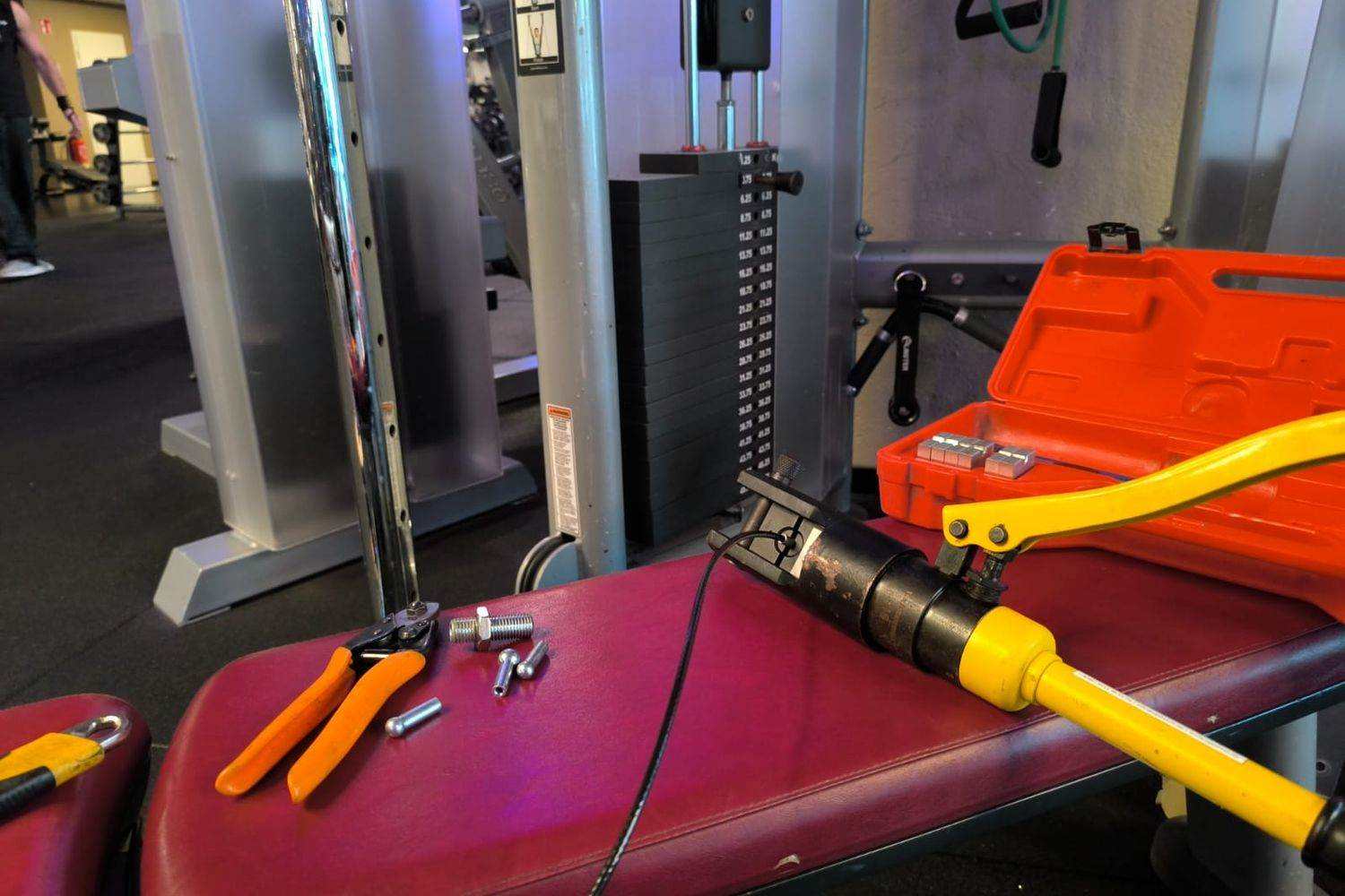 Hydraulic press crimping a new steel cable end beside a cable pulley station