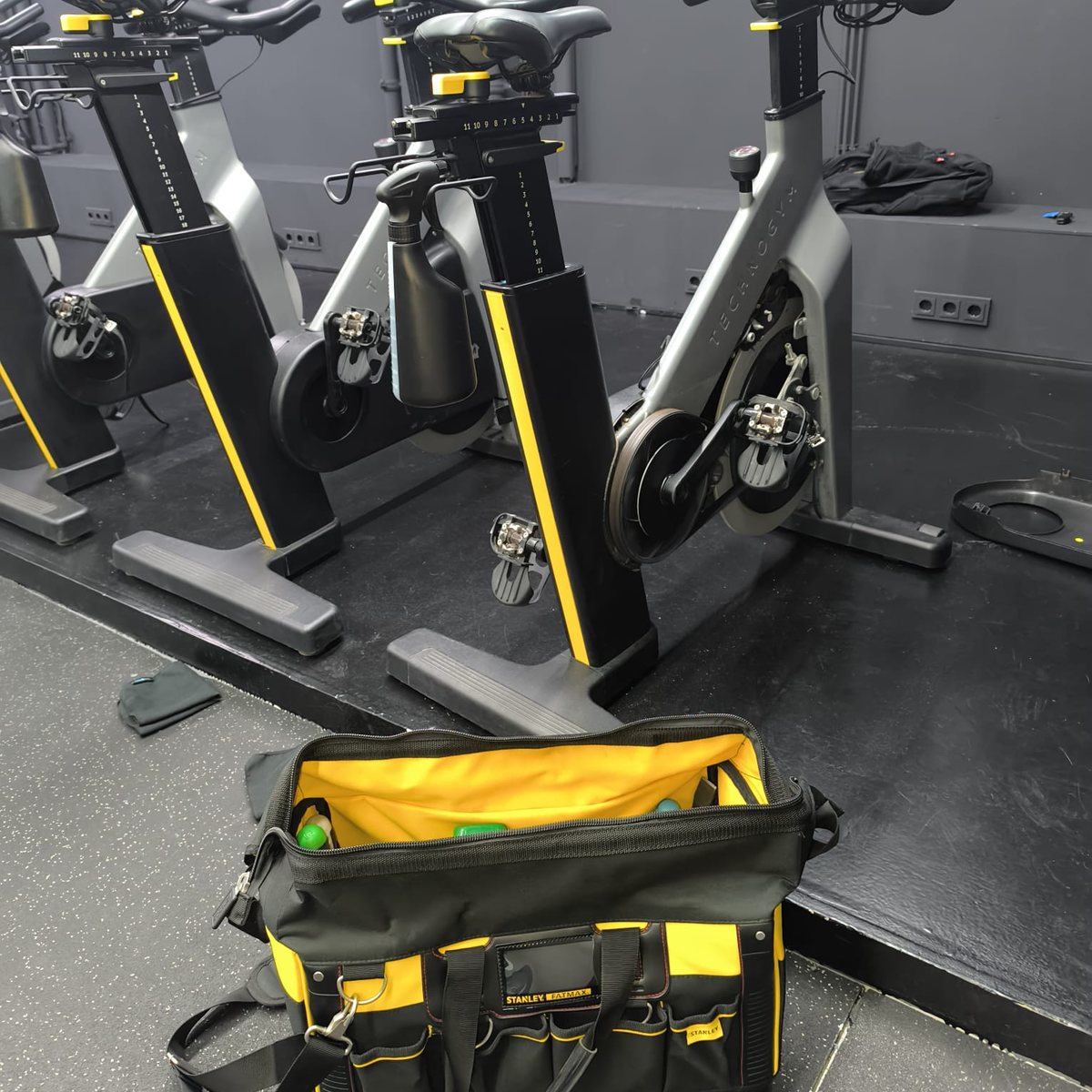 Rangée de vélos indoor cycling, sacoche à outils ouverte et pulvérisateur pendant la visite d’entretien