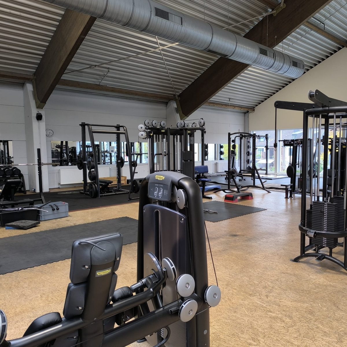 Zone de musculation d’une salle avec appareils à charge guidée, station à câbles et racks